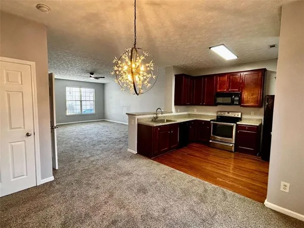 a kitchen with stainless steel appliances granite countertop a sink dishwasher a stove and a refrigerator with wooden floor