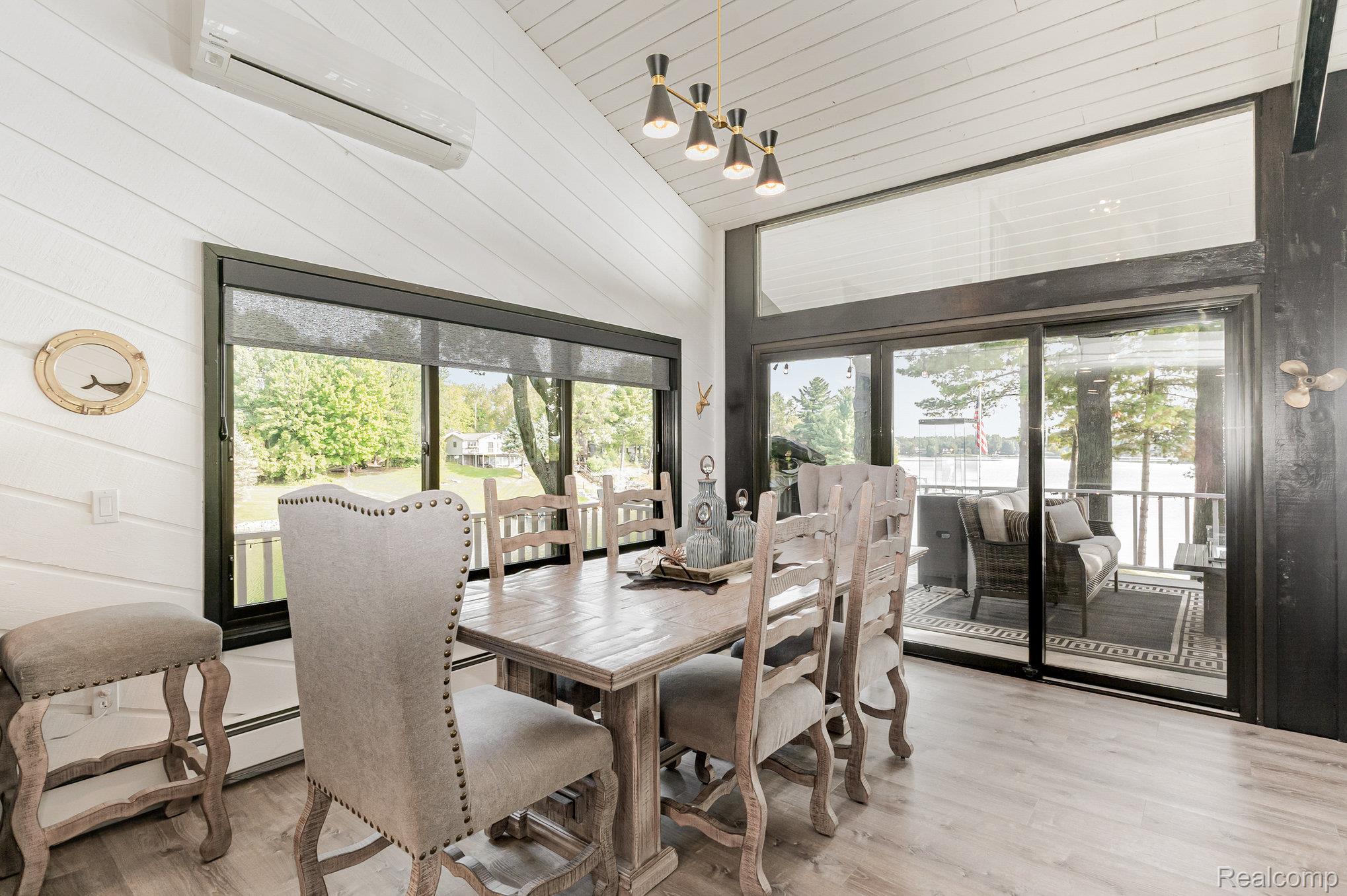 2380 Islanders Way Gladwin, MI 48624 - Photo 18 of 48 Dining area featuring light wood-style floors, wooden walls, a vaulted wood ceiling, and healthy amount of natural light