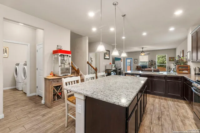 a kitchen with stainless steel appliances granite countertop sink refrigerator and wooden floor