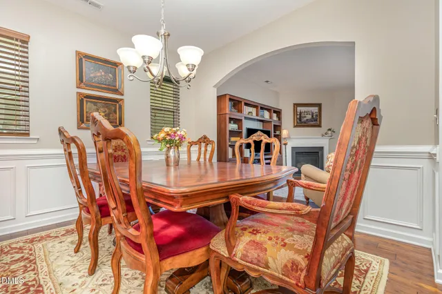 a dining room with wooden floor a chandelier a glass table and chairs