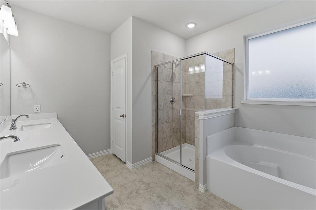 1329 Frio Drive Springtown, TX 76082 - Photo 18 of 25 Bathroom featuring a white dual vanity with undermount sinks, a walk-in shower with tile surround and glass enclosure, a built-in bathtub, and a frosted window