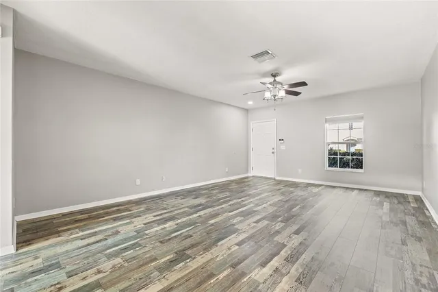 wooden floor in an empty room with a chandelier fan
