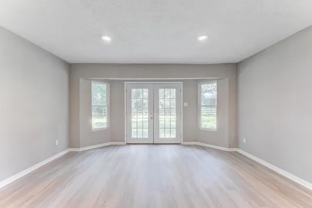an empty room with wooden floor and windows