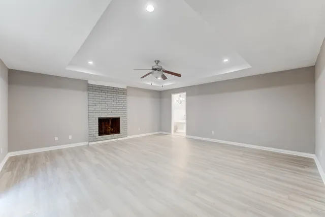 an empty room with wooden floor fireplace and windows