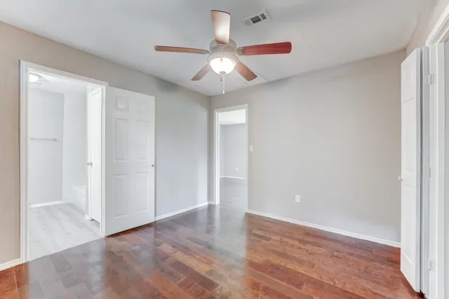 an empty room with wooden floor chandelier fan and closet area