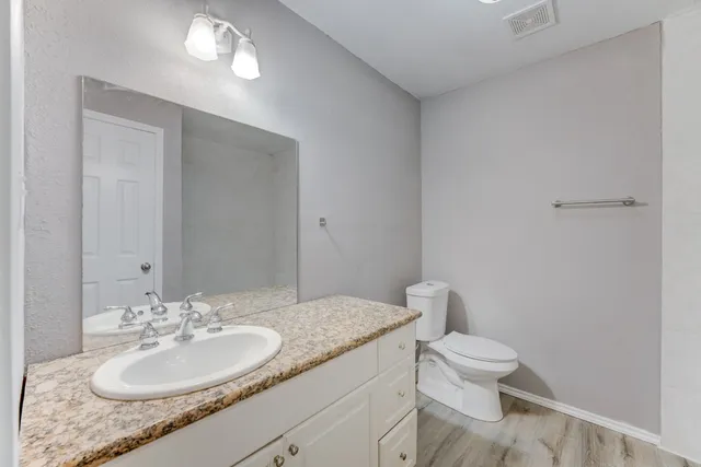 a bathroom with a granite countertop sink a toilet and a mirror