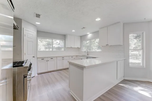 a kitchen with a sink wooden floor and white cabinets