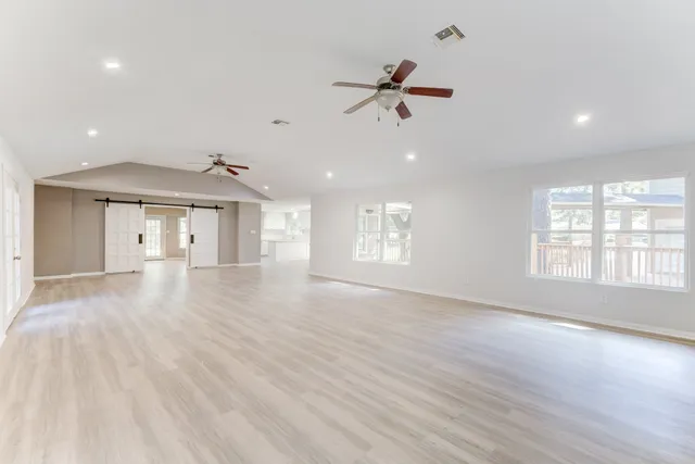 a view of an empty room with a window and wooden floor
