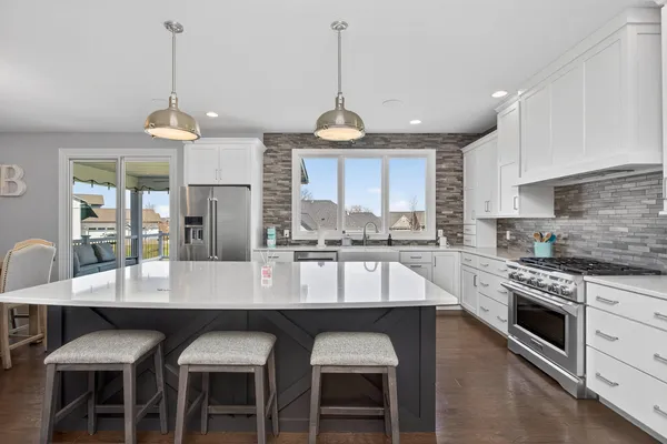 a kitchen with stainless steel appliances granite countertop a sink a stove a refrigerator and island with wooden floor