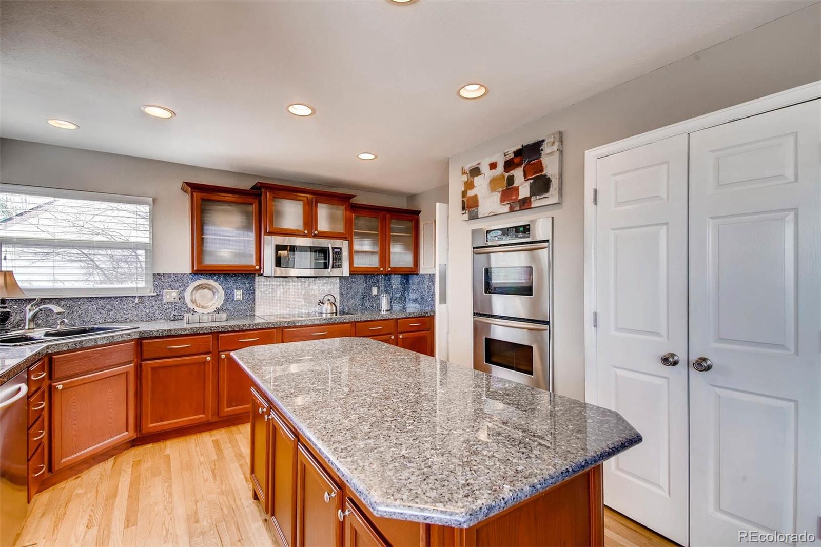 1665 Spring Water Lane Highlands Ranch, CO 80129 - Photo 11 of 34 a kitchen with stainless steel appliances granite countertop a refrigerator a stove and a sink with wooden floor