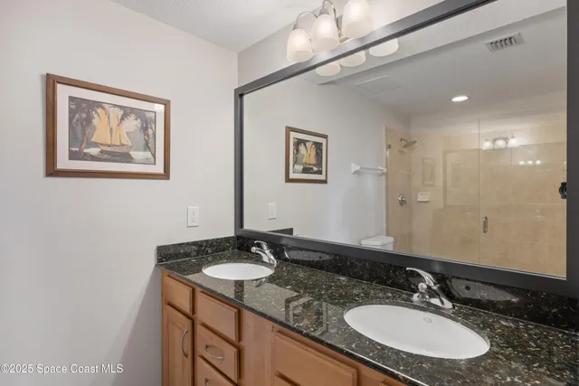a bathroom with a granite countertop toilet a sink and shower