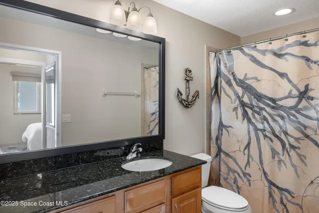 a bathroom with a granite countertop sink and a mirror with toilet