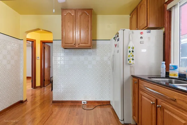 a kitchen with a refrigerator and wooden floor