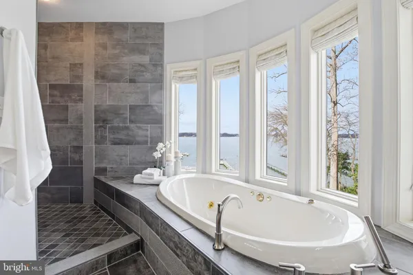 a bathroom with a tub a sink and a large mirror