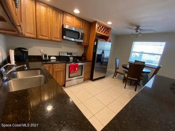 a kitchen with kitchen island granite countertop a stove top oven a sink a dining table and chairs with wooden floor