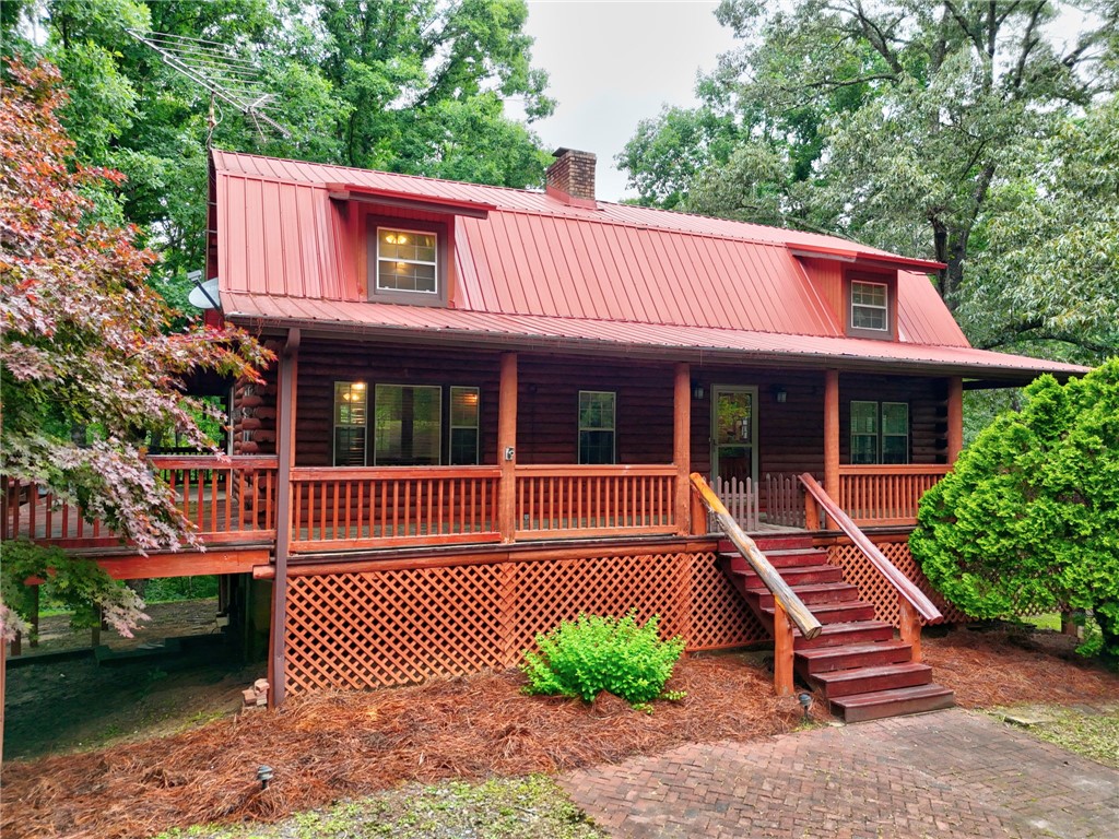237 Spring Valley Road Liberty, SC 29657 - Photo 1 of 50 A charming log cabin awaits, nestled among verdant trees with a spacious porch.