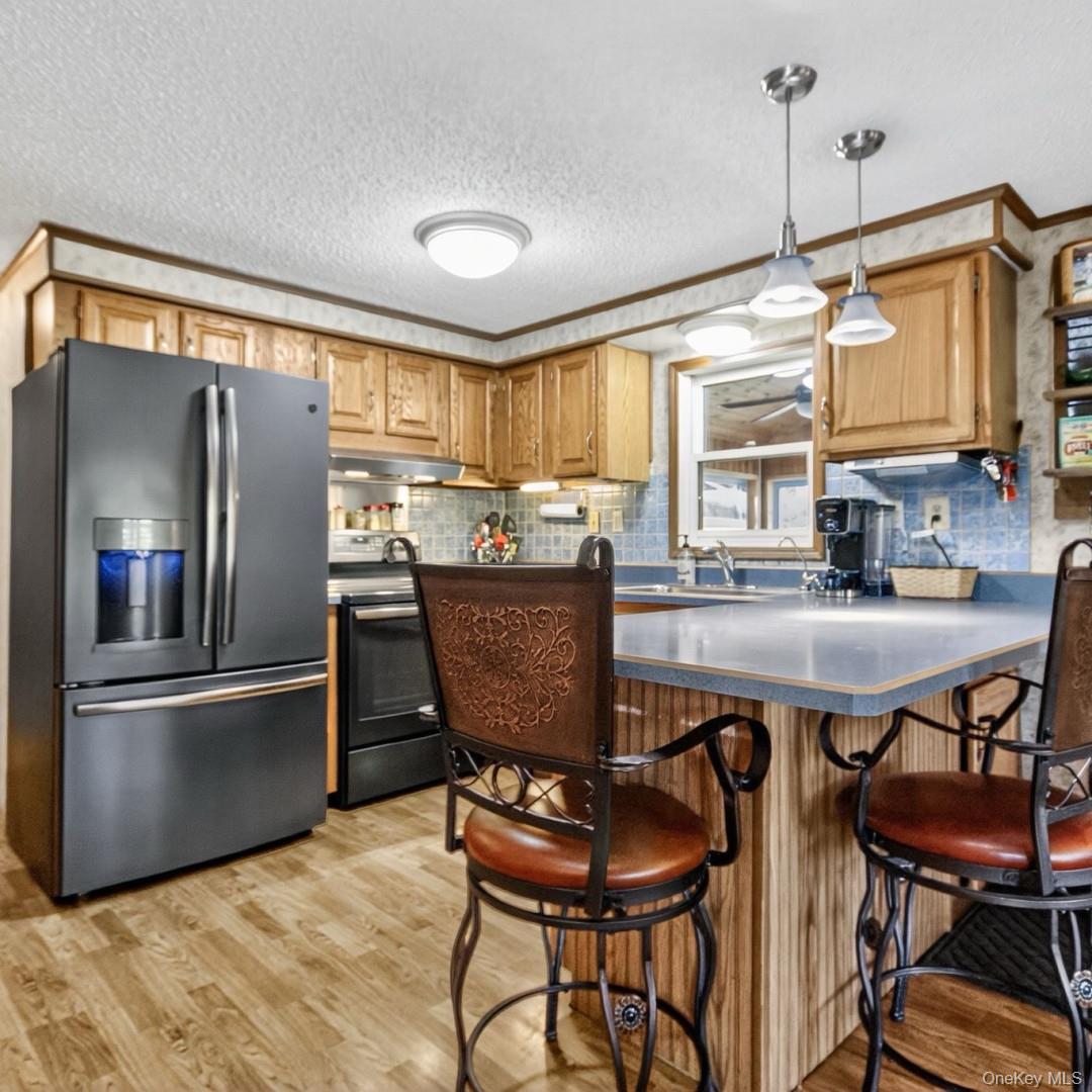 69 Crabby Road Loch Sheldrake, NY 12759 - Photo 13 of 20 a kitchen with stainless steel appliances granite countertop a dining table chairs refrigerator and sink