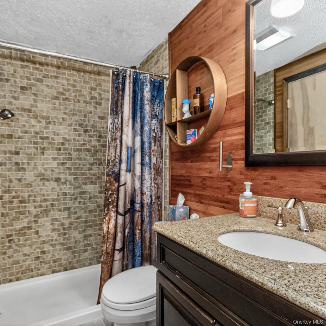 69 Crabby Road Loch Sheldrake, NY 12759 - Photo 20 of 20 a bathroom with a granite countertop toilet sink and mirror