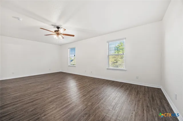 a view of an empty room with a window and wooden floor