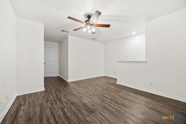 an empty room with wooden floor and a ceiling fan
