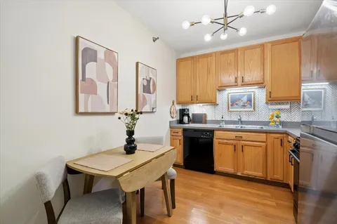 a kitchen with stainless steel appliances a sink a stove a refrigerator dining table and chairs