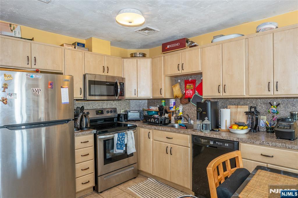 75 Union Street, Unit 5E Hackensack, NJ 07601 - Photo 14 of 24 a kitchen with stainless steel appliances granite countertop a stove a sink dishwasher and a refrigerator with wooden cabinets