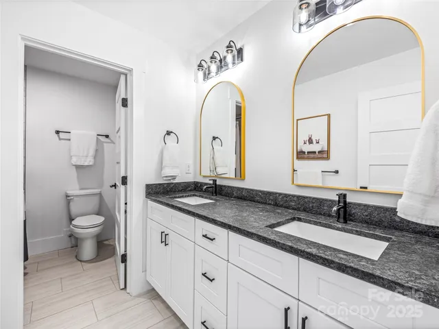 a bathroom with a granite countertop toilet sink and mirror