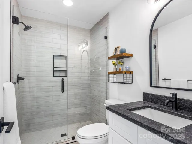 a bathroom with a granite countertop sink a toilet and shower