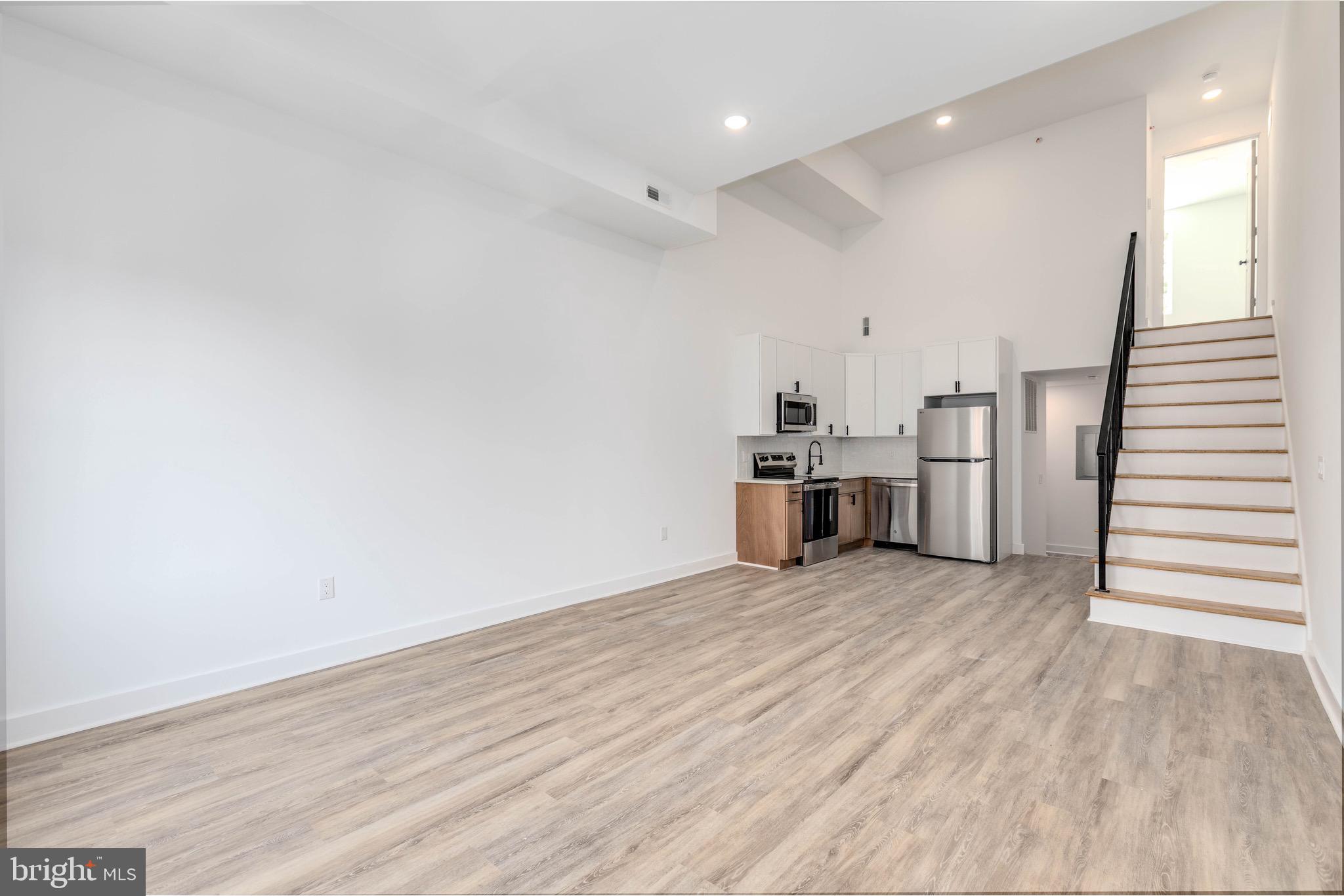 a view of a kitchen with wooden floor electronic appliances and stairs