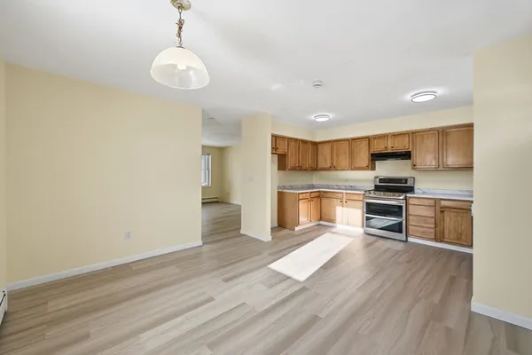 a view of an empty room with window and wooden floor