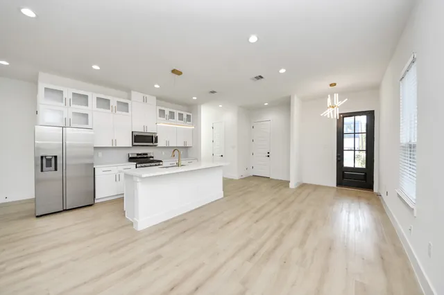 a large kitchen with stainless steel appliances kitchen island a large counter top and a refrigerator