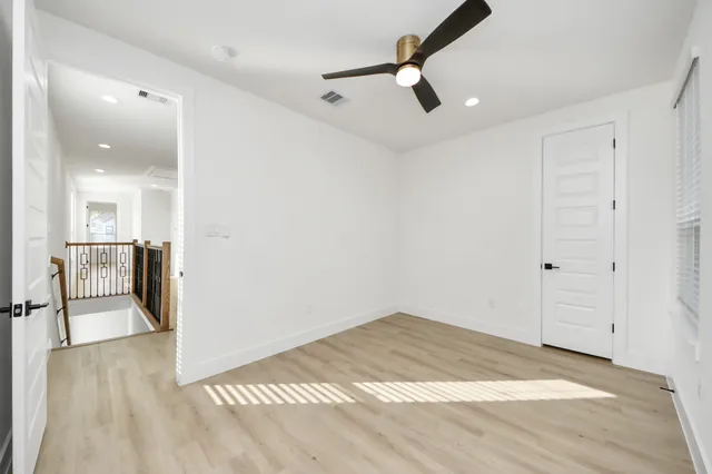 a view of an empty room with a window and wooden floor