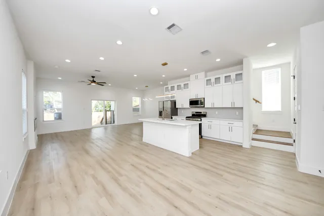 a kitchen with stainless steel appliances kitchen island wooden floors and white cabinets