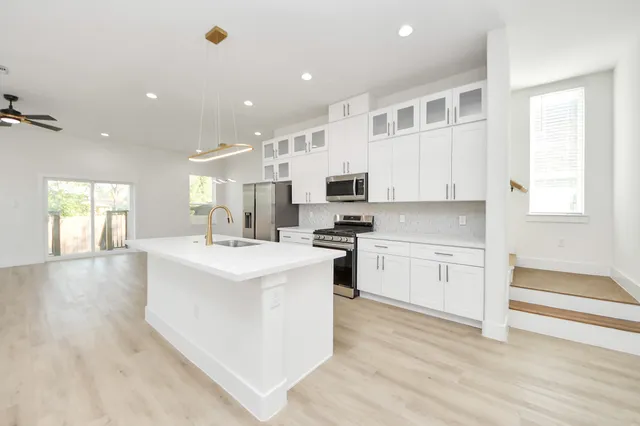 a large kitchen with stainless steel appliances a large counter top and a wooden floors