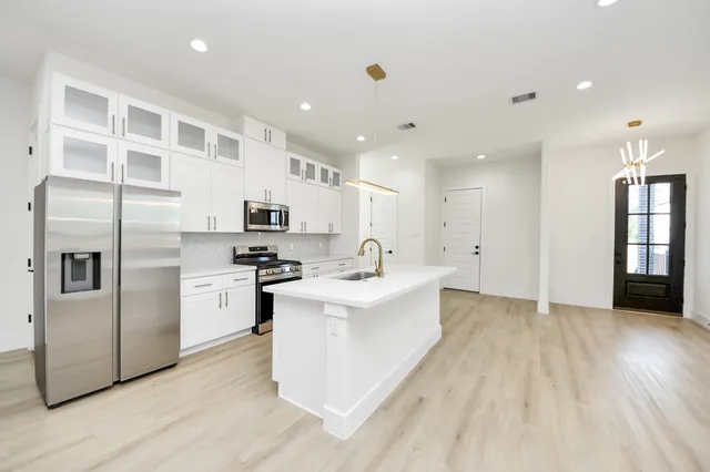 a kitchen with stainless steel appliances kitchen island granite countertop a stove a sink and a refrigerator