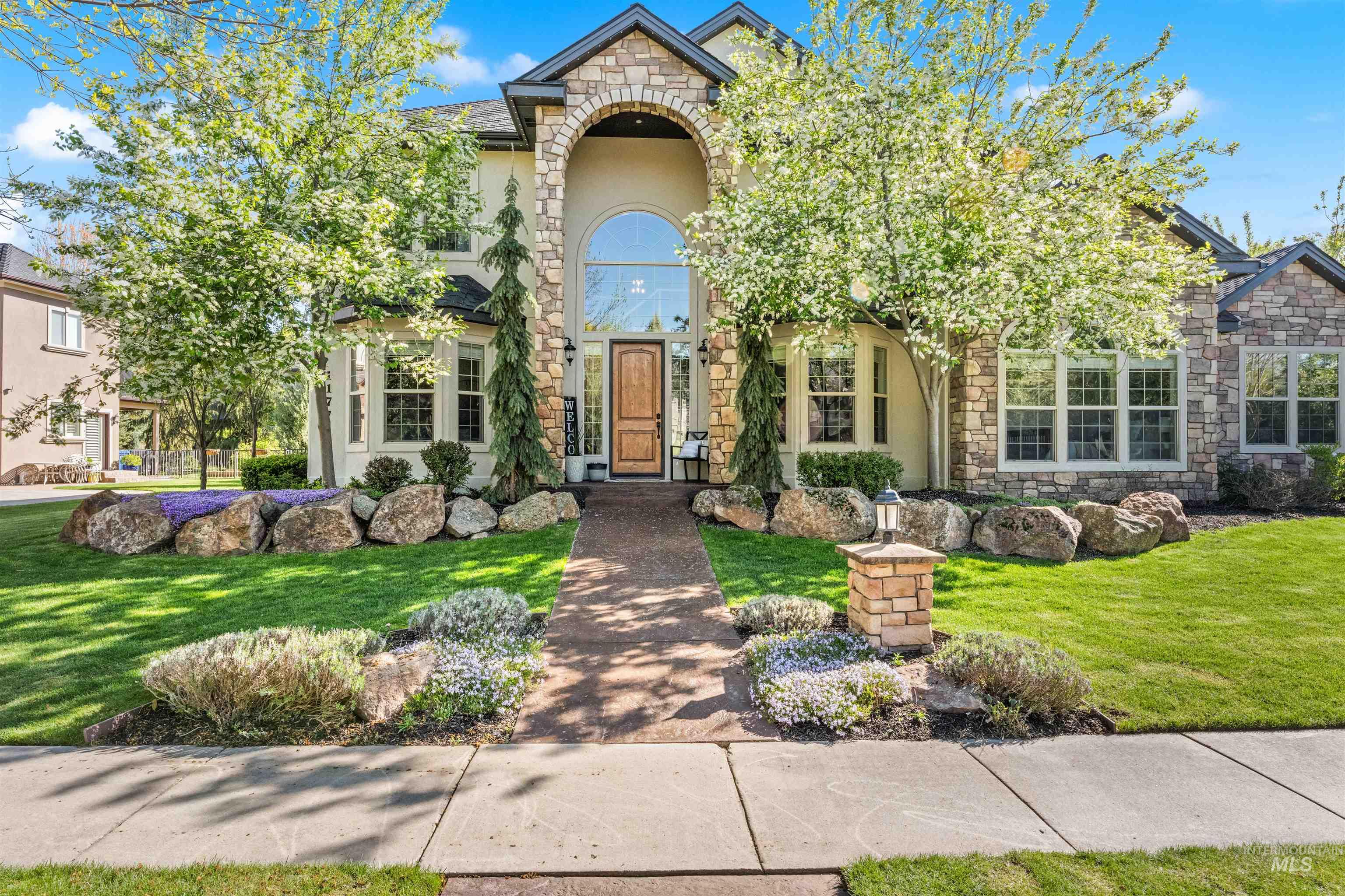 View of front of house featuring stone siding, a front lawn, and stucco siding