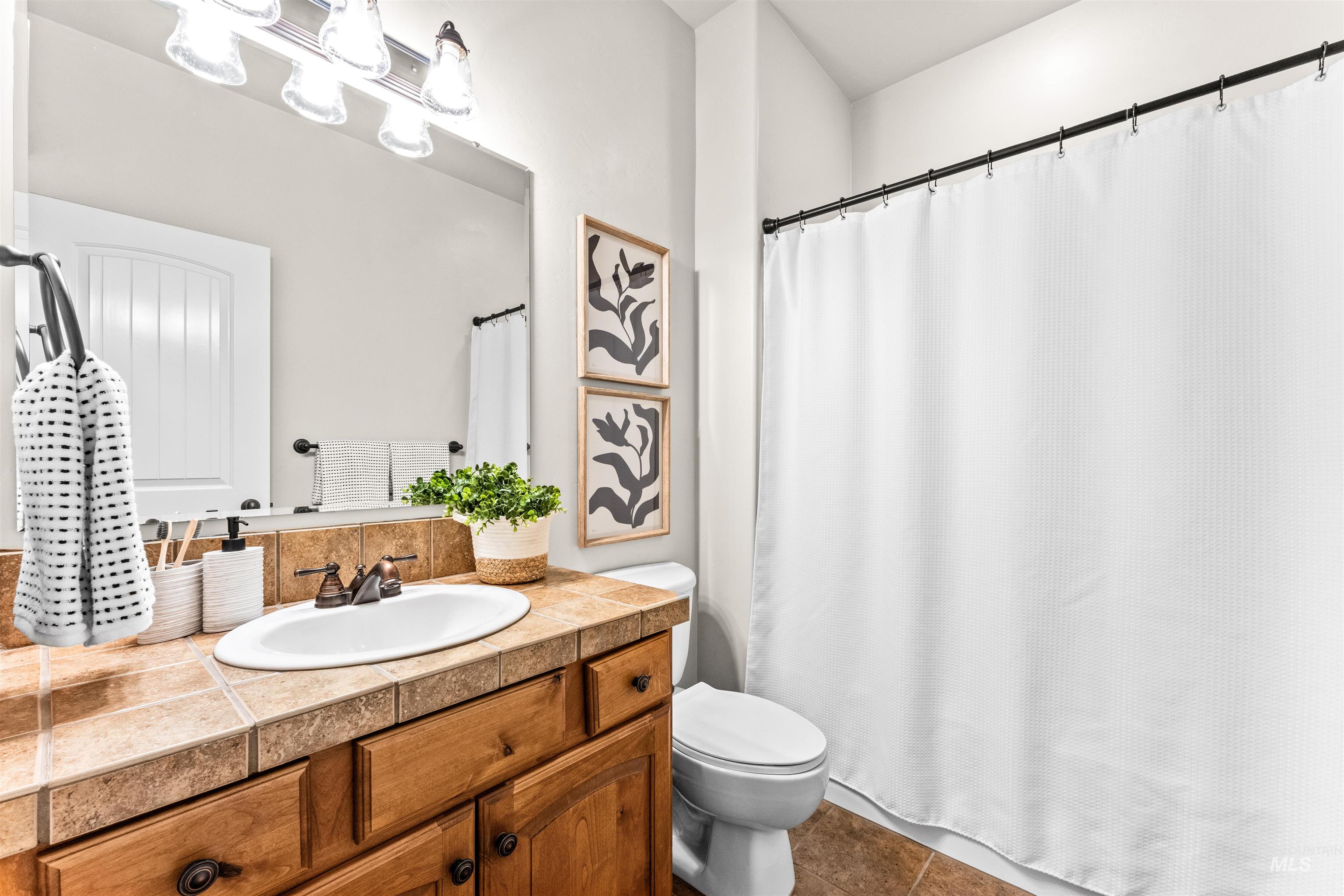 1177 East Riversong Drive Eagle, ID 83616 - Photo 24 of 36 Full bathroom featuring vanity, curtained shower, and dark tile patterned floors