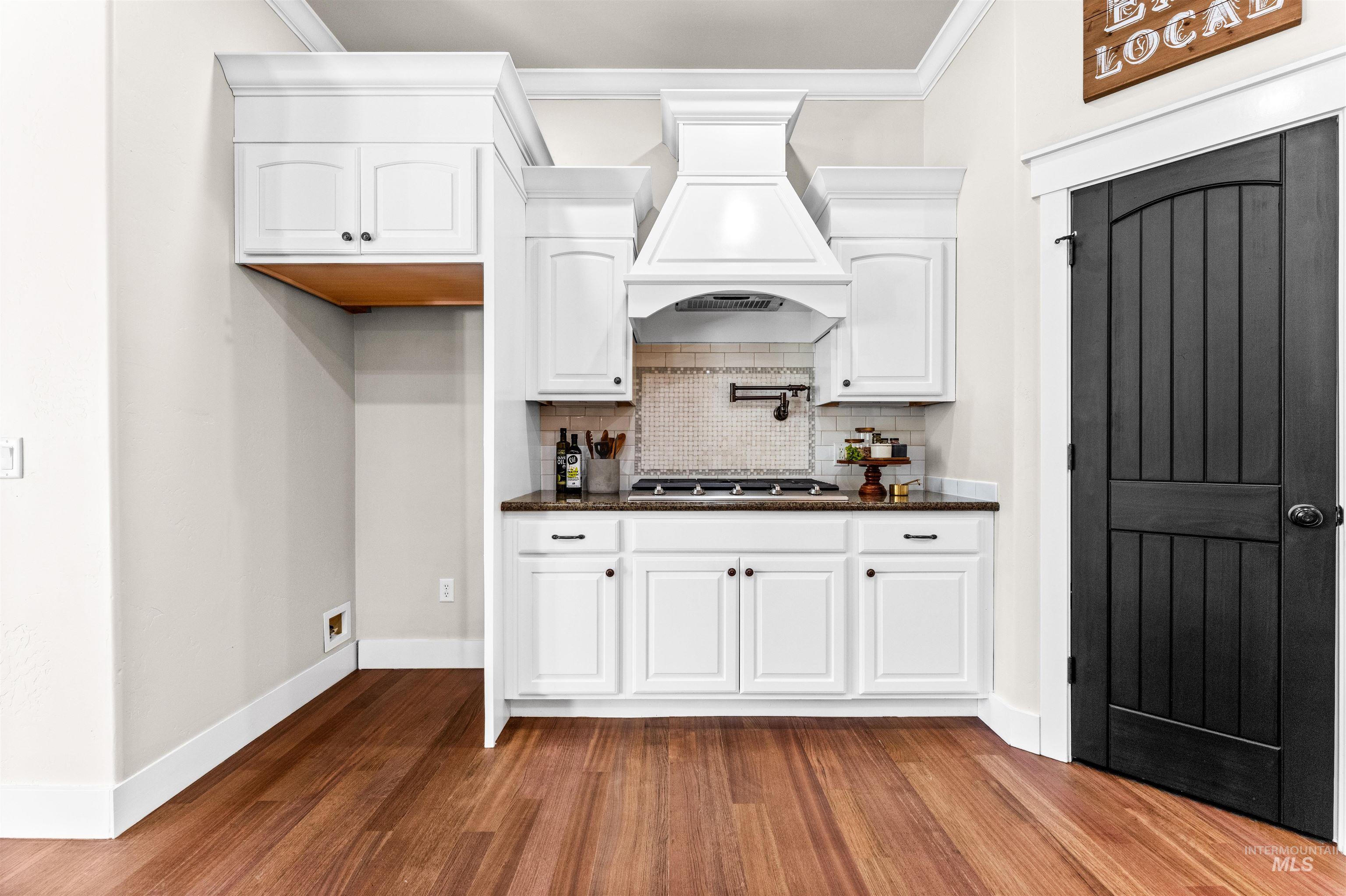 1177 East Riversong Drive Eagle, ID 83616 - Photo 7 of 36 Kitchen featuring white cabinets, dark stone countertops, dark wood finished floors, crown molding, and decorative backsplash