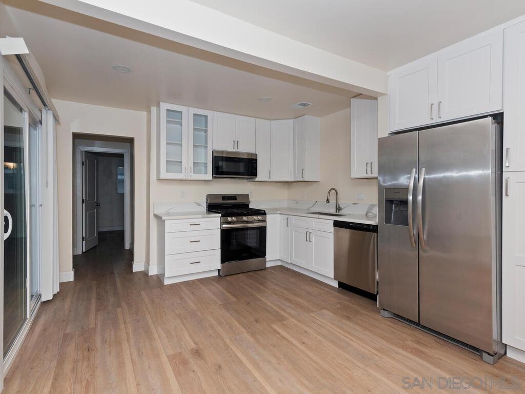 1027 Chestnut Street Escondido, CA 92025 - Photo 6 of 35 a kitchen with a refrigerator a stove top oven a sink and dishwasher with wooden floor