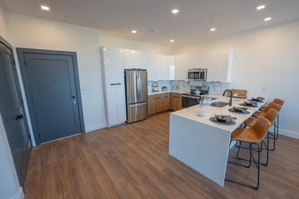 a kitchen with kitchen island a stove a refrigerator and a dining table with wooden floor