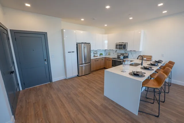 a kitchen with kitchen island a stove a refrigerator and a dining table with wooden floor