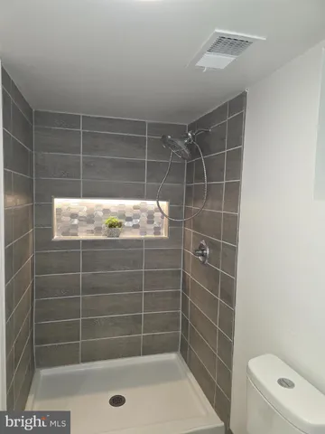 a bathroom with a granite countertop bathtub shower sink vanity and toilet