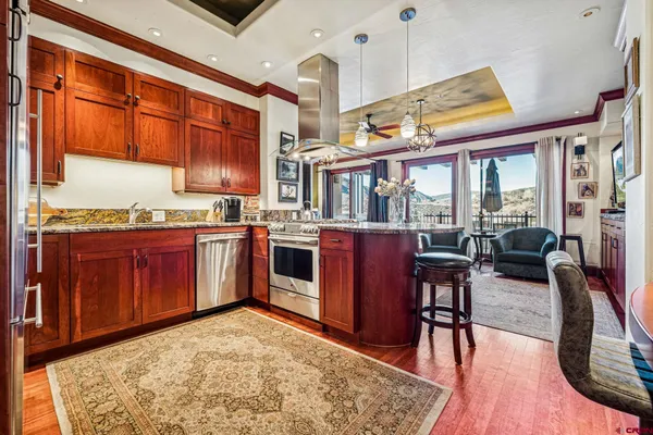 a view of a kitchen with kitchen island granite countertop wooden cabinets stainless steel appliances a dining table and chairs
