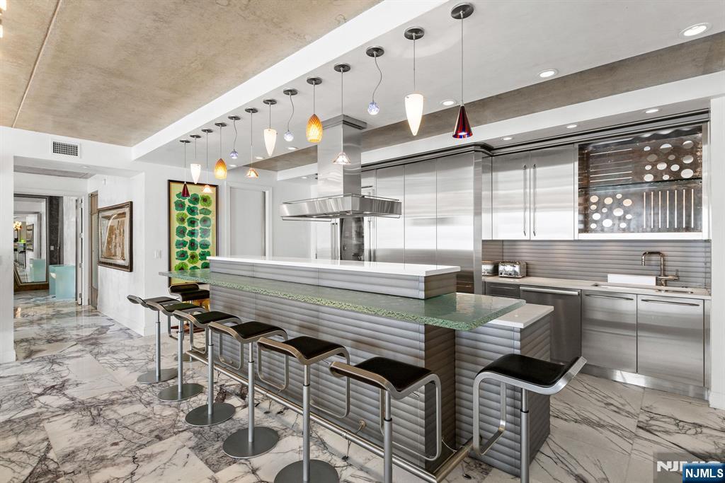 1055 River Road, Unit PH 8 Edgewater, NJ 07020 - Photo 6 of 30 a kitchen with granite countertop a stove a sink and chairs