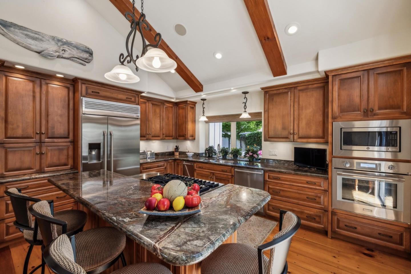 9546 Maple Court Carmel, CA 93923 - Photo 16 of 36 a kitchen with stainless steel appliances kitchen island granite countertop a table chairs in it and wooden floors