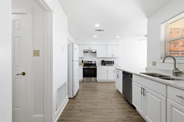 a kitchen with white cabinets appliances and a window