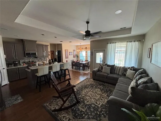 a living room with furniture wooden floor and kitchen view