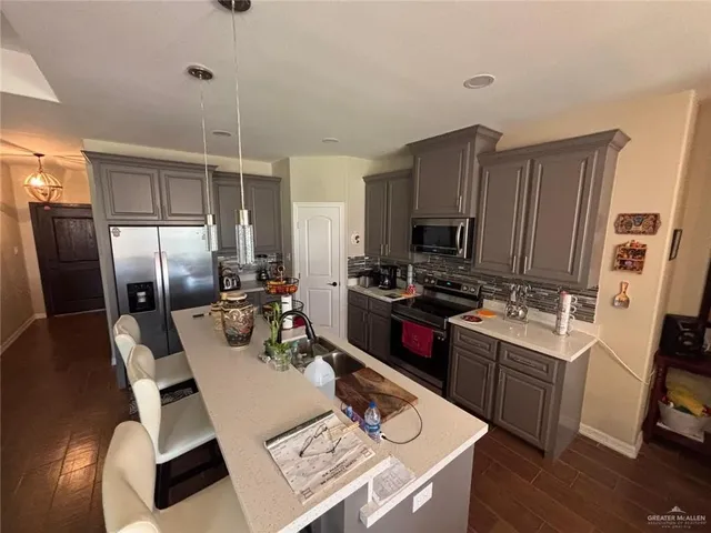 a kitchen with a refrigerator a stove a sink dishwasher a dining table and chairs with wooden floor