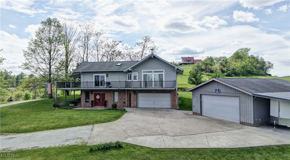Traditional home with a front yard, brick siding, a wooden deck, concrete driveway, and an attached garage