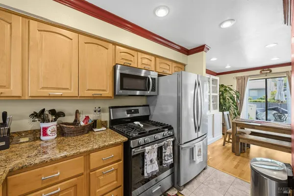a kitchen with stainless steel appliances granite countertop a stove a sink dishwasher and a refrigerator with wooden floor